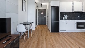 Una cocina moderna con armarios blancos, un refrigerador negro y piso de madera.