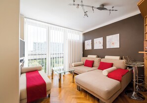 A modern living room with a sofa set, a glass coffee table, and a ceiling light fixture. - Chłodna Comfort Apartment (Warszawa)
