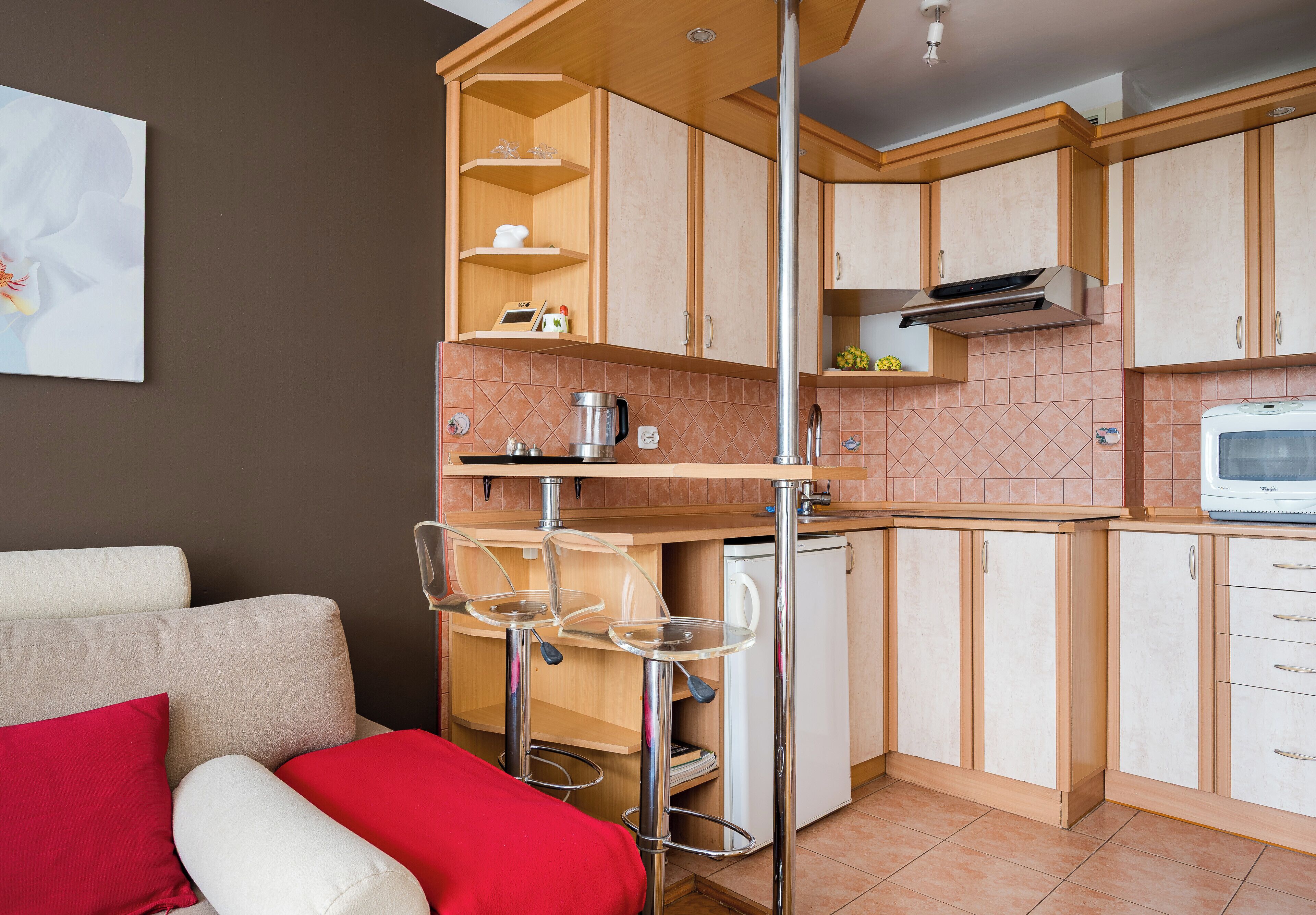 Una cucina compatta con mobili in legno, un forno a microonde integrato e una macchina da caffè.