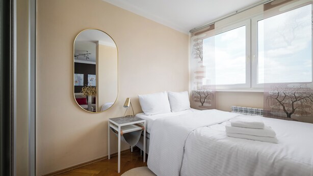 Ein Schlafzimmer mit einem Bett, einem Nachttisch, einem Spiegel und einem Fenster.