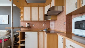 Eine kompakte Küche mit Holzschränken, einer eingebauten Mikrowelle und einem kleinen Kühlschrank.