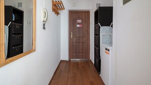 Un corridoio con una porta in legno, un telefono e un appendiabiti.
