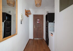Un couloir avec une porte en bois, un téléphone et un porte-manteau.
