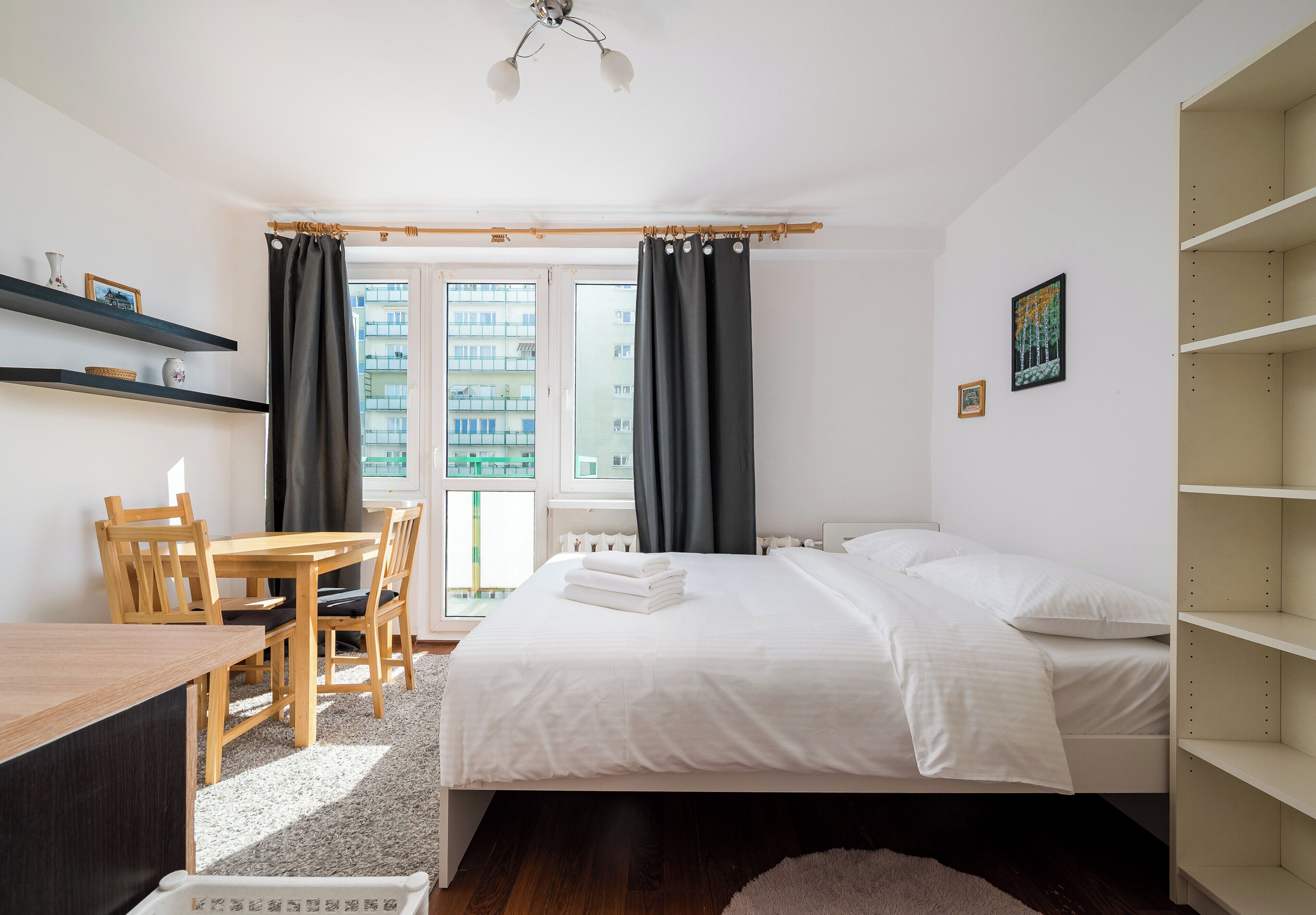 A bedroom with a bed, a desk, a chair, and a window with curtains.