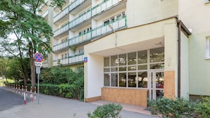 Un edificio a più piani con ingresso al piano terra, un segnale che indica divieto di parcheggio e una targa con il numero civico.