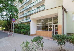 Un immeuble à plusieurs étages, avec une entrée au niveau du sol, un panneau indiquant qu’il est interdit de se garer et un autre panneau indiquant le numéro de l’immeuble.