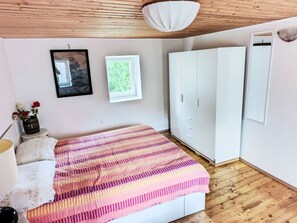 Quarto com cama, guarda-roupa, janela e um quadro fixado na parede.
