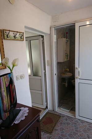 Casa de banho com sanita, lavatório e armário. Uma porta dá para outro espaço.