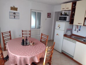 A dining area with a table set for two, a refrigerator, a microwave, and a sink. - Vollständig eingerichtetes Haus mit privater Sonnenterrasse by Interhome (Lecevica)