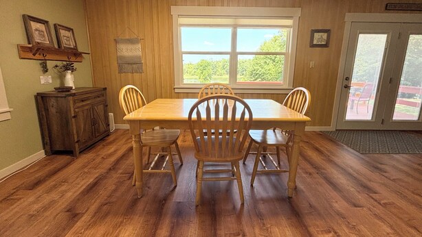 Un'area pranzo con un tavolo e sedie in legno, una finestra vista e una porta con pannello in vetro.