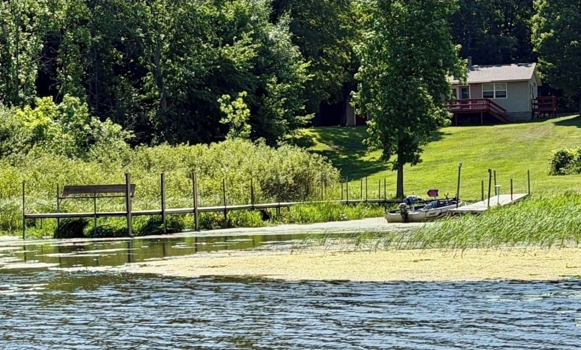 Une propriété au bord du lac, avec un quai, un bateau et une maison en arrière-plan.