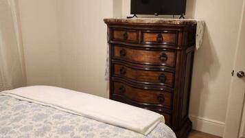 Une chambre à coucher avec un lit, une commode et un téléviseur posé sur la commode.