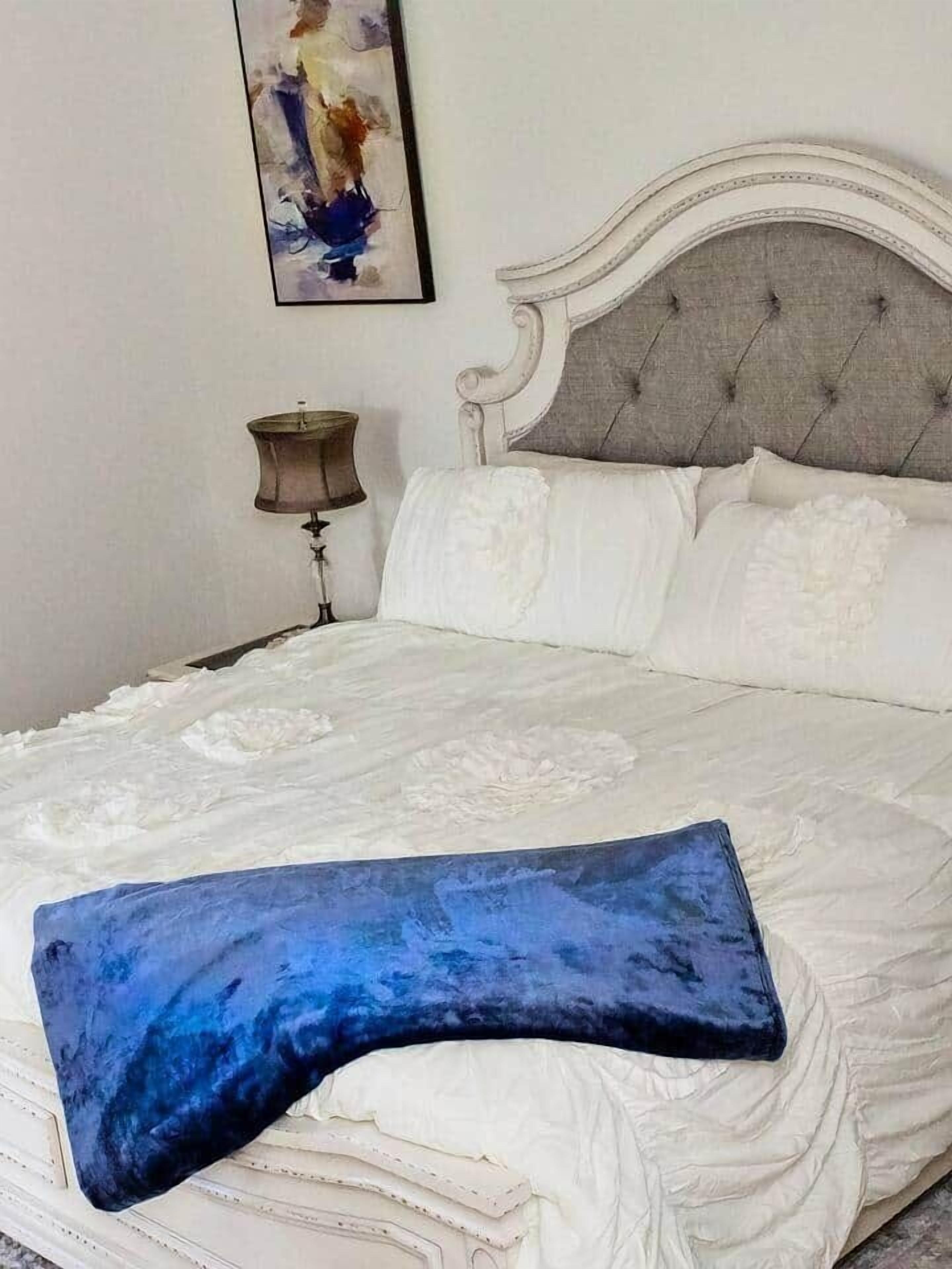 Een bed met een gestoffeerd hoofdbord, een witte spreideken en een blauw kussen.