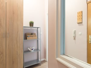 A hallway with a wooden wardrobe, a metal shelf unit with storage boxes and a decorative item, and a door with a light switch and a phone. - für 2 Personen ca. 30 m² in Rijeka, Kvarner Bucht (Gespanschaft Primorje-G by Interhome (Rijeka)