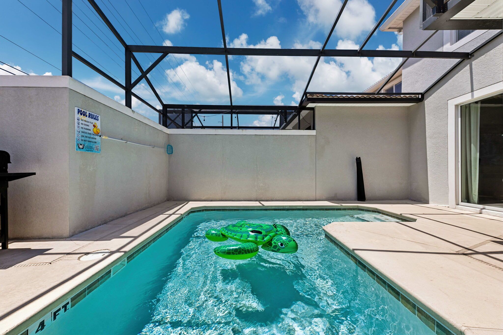 A swimming pool with a pool rule sign, a sunshade, and a clear sky.