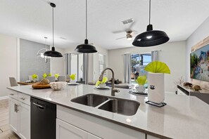 A modern kitchen with a double sink, pendant lighting, and a large window. - Brand New | 4Bd Private Pool, Resort Near Disney  4993 (Kissimmee)