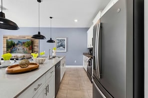 A modern kitchen with a grey refrigerator, stainless steel appliances, and a wooden countertop. - Brand New | 4Bd Private Pool, Resort Near Disney  4993 (Kissimmee)