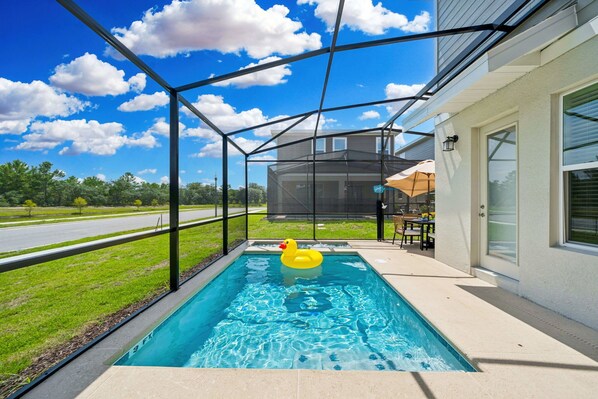 Ein rechteckiger Pool mit Sicherheitsnetz, einem gelben Schwimmdackel und einer Terrassenanlage mit Gartenmöbeln.