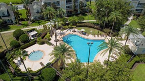 A large swimming pool surrounded by palm trees and lounge chairs, with a small circular pool nearby. - Brand New 5BR 5BA Villa w Pool, Spa & Game Room 7800 (Kissimmee)