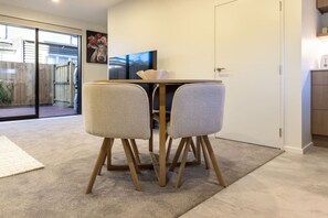 A dining area with a table and chairs, a television, and a door leading to a garage.