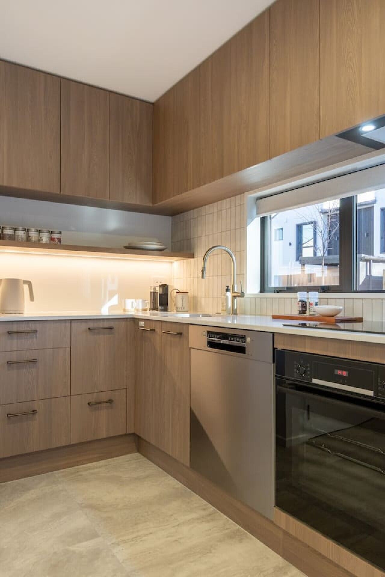 A modern kitchen with wooden cabinets, a stainless steel sink, and a built-in oven.