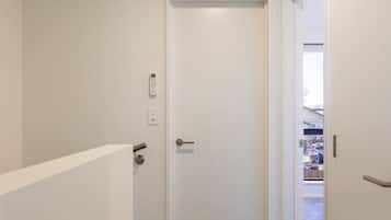A narrow hallway with a closed door, a white air conditioning unit above, and a carpeted floor.