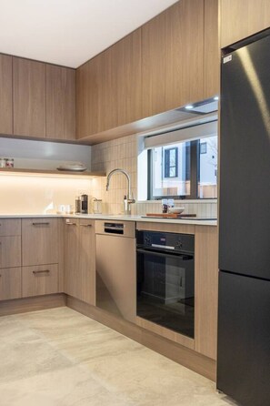 A modern kitchen with wooden cabinets, a stainless steel refrigerator, and built-in appliances.