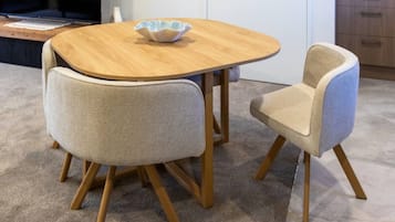 A round wooden table with a bowl on it, flanked by two upholstered chairs with wooden legs.
