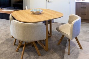 A round wooden table with a bowl on it, flanked by two upholstered chairs with wooden legs.
