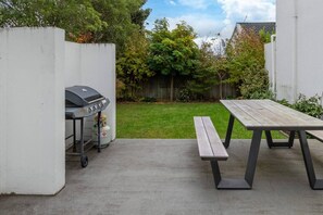Un espace extérieur aménagé avec un barbecue et une table en bois entourée de bancs.