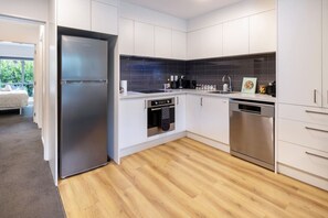 Eine moderne Küche mit weißen Schränken, einem Edelstahl-Kühlschrank, einem Geschirrspüler und einer schwarzen Küchenzeile.
