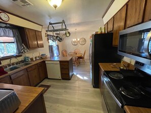 A kitchen with wooden cabinets, a microwave, a stove, and a dining area with chairs.