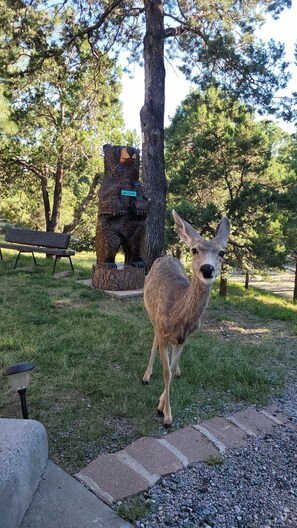A park with a deer, a wooden sculpture, and a bench.