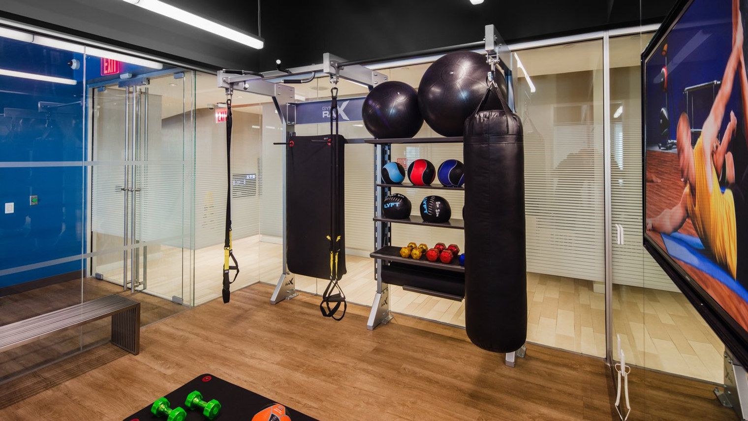 A gym with exercise equipment, a punching bag, and a TV screen.