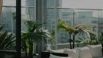 A rooftop lounge with a sofa and potted plants.