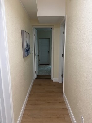 Ein Flur mit Holzboden, beigen Wänden und einer Tür am Ende.