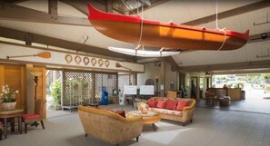 A spacious lobby with wicker furniture, a large red boat decoration, and a reception desk. - Adorable 1-bedroom Kapaa condo w/ AC on the Bike path in ocean front Pono Kai (Kapaa)