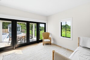 A room with a large sliding glass door leading to an outdoor patio area with a pool and furniture.