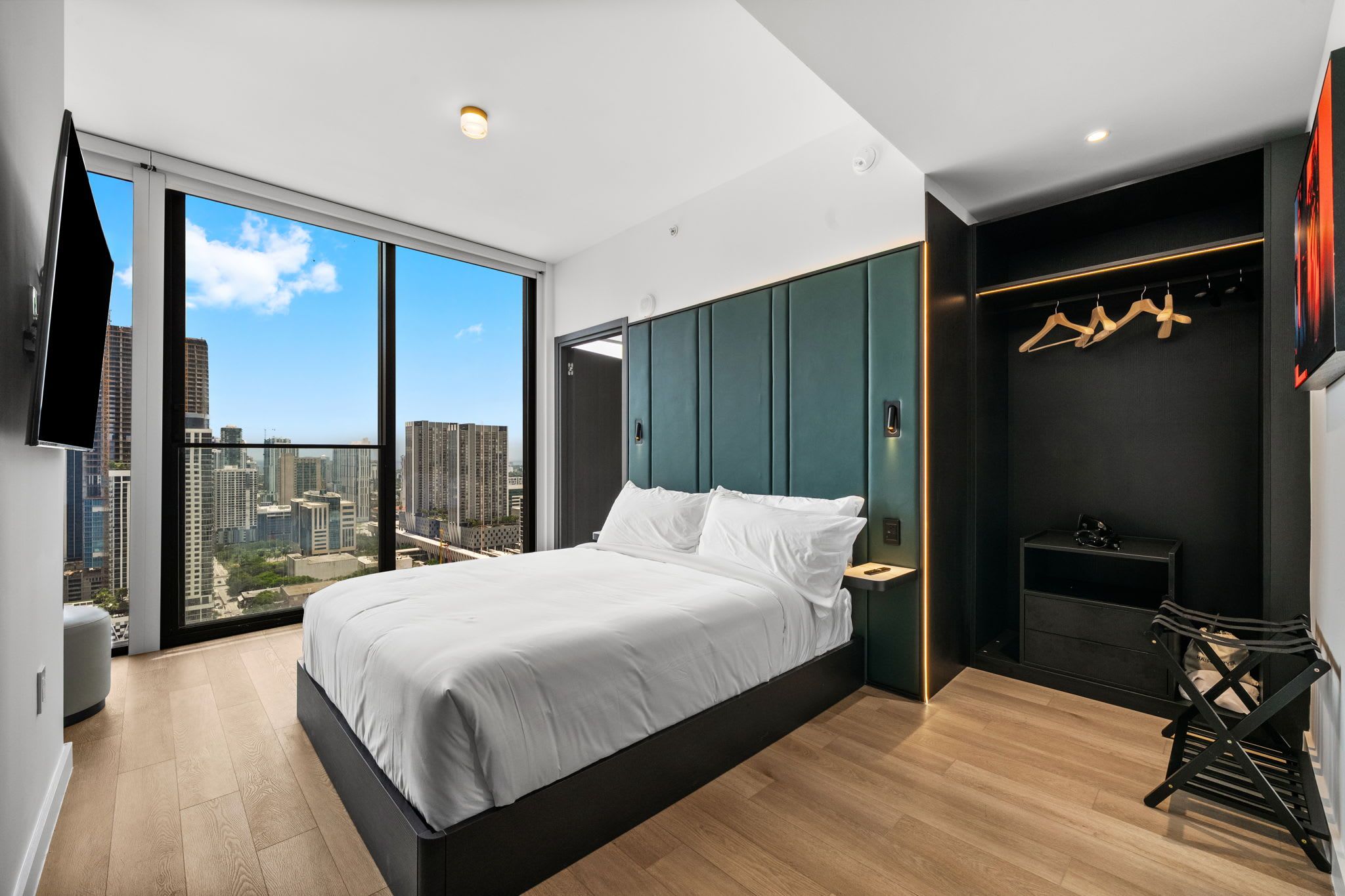 A modern bedroom with a large bed, a view of the city, and a minimalist design.