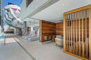 A modern hotel lobby with a large hand sculpture, a pool, and a reception area with wooden paneling. - Adjoining Suite at the E11even Residences (Miami)