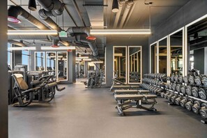 A gym with exercise equipment, weight racks, and large windows. - 25th Floor Adjoining Suite at the E11even Residences (Miami)