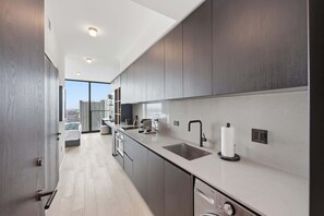 A modern kitchen with a large window, a sink, and a dishwasher. - Deluxe E11EVEN Suite with Elite Amenities (Miami)