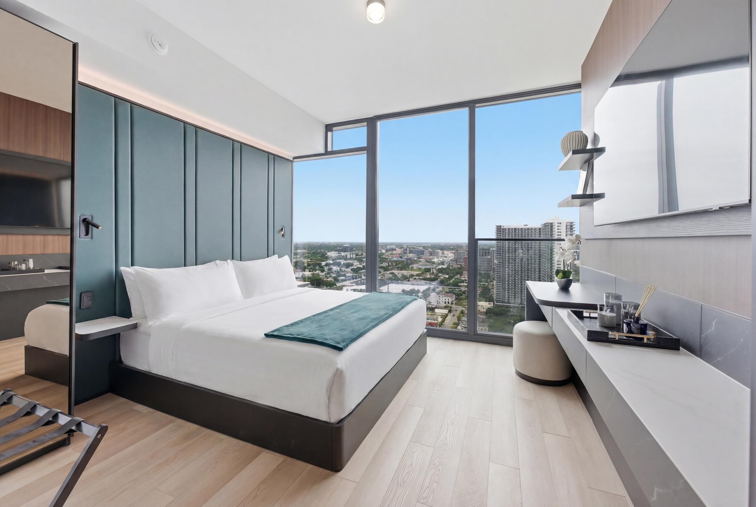 Ein modernes Hotelzimmer mit einem großen Bett, einem Schreibtisch und Blick auf die Stadt.