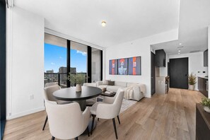 Ein modernes Wohnzimmer mit Essbereich, großen Fenstern und Blick auf die Stadtlandschaft.