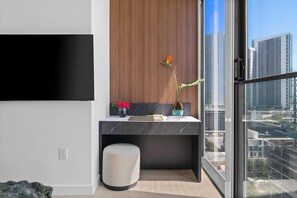 Ein modernes Hotelzimmer mit großem Fenster, einem flachbildfernseher an der Wand, einem kleinen runden Hocker und einer Holzvertäfelung über der Theke.
