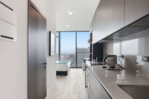 Eine moderne Küche mit einem großen Fenster, einem Bett und Blick auf die Stadt.