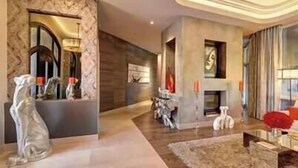 A modern interior with a fireplace, decorative sculptures, and a large mirror. - $5Mil Luxury Estate - Pickleball Pool Hot Tub (Scottsdale)