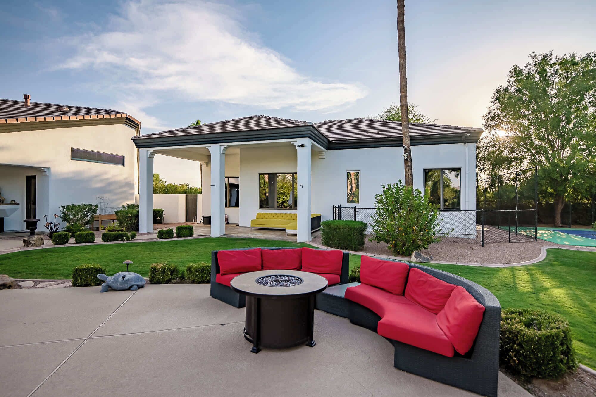 Un patio extérieur moderne avec un canapé incurvé, une table ronde et une piscine en arrière-plan.