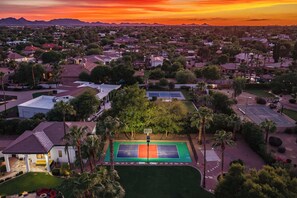 Vue aérienne d’un quartier résidentiel avec des maisons, un court de tennis et, au loin, une chaîne de montagnes.