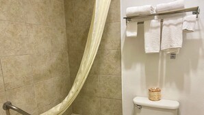 Un baño con bañera, inodoro y un perchero con toallas dobladas.